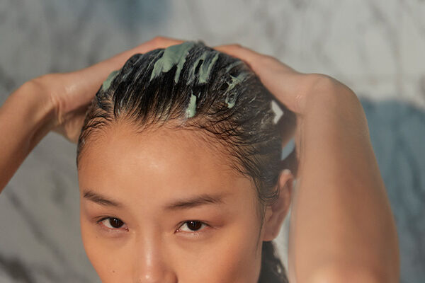 person washing hair with pre-cleanse shampoo