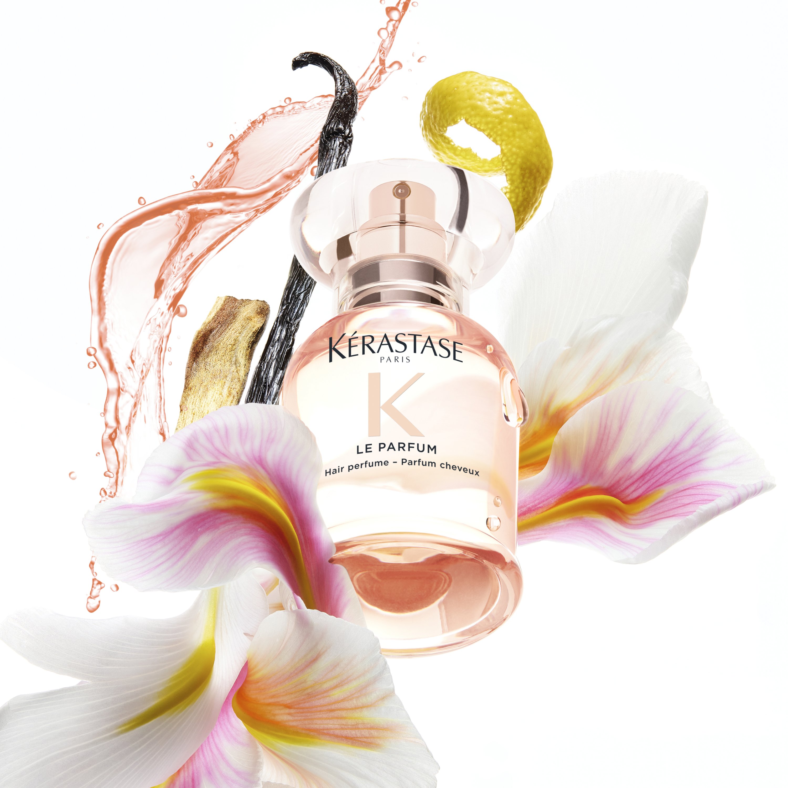 Kérastase Le Hair Parfum bottle displayed with floral petals, vanilla bean, and citrus elements, highlighting the fragrance notes and luxurious scent profile.